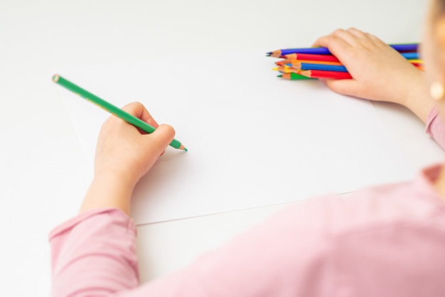 Child is drawing by colored pencils.