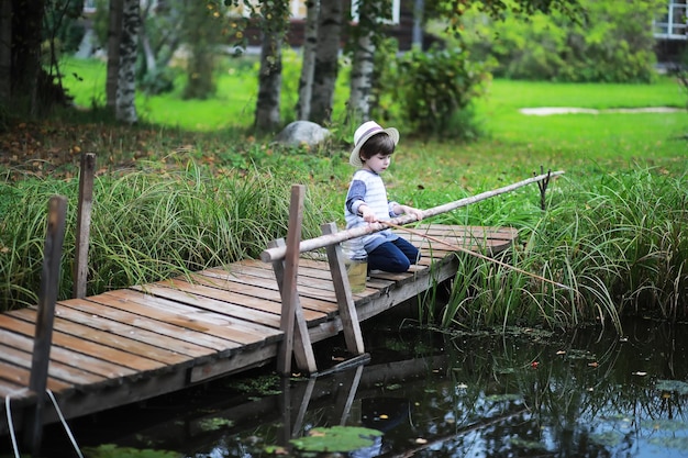 A child is fishing in the autumn morning. Autumn sunset on the pond. A fisherman with a fishing rod on the walkway.