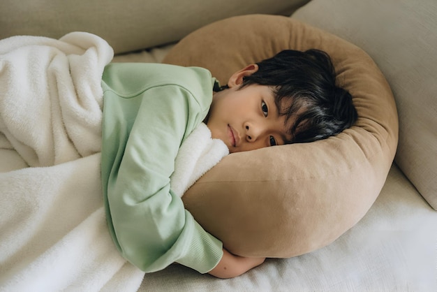 a child is laying on a couch with a green blanket