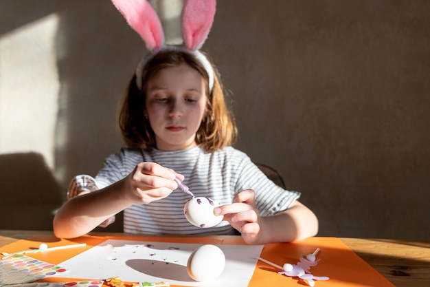 Child is making easter eggs decoration preparation and funcute girl in easter bunnies ears prepares