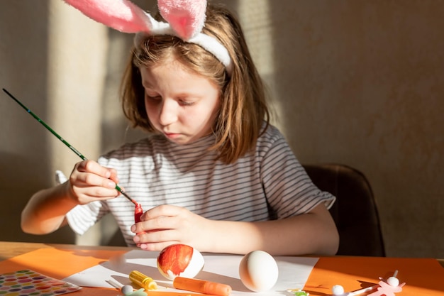 Child is making easter eggs decoration preparation and funcute girl in easter bunnies ears prepares