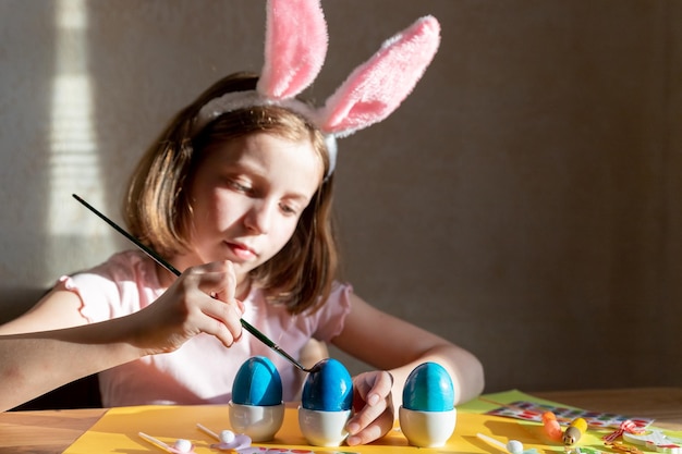 Child is making easter eggs decoration preparation and funcute girl in easter bunnies ears prepares