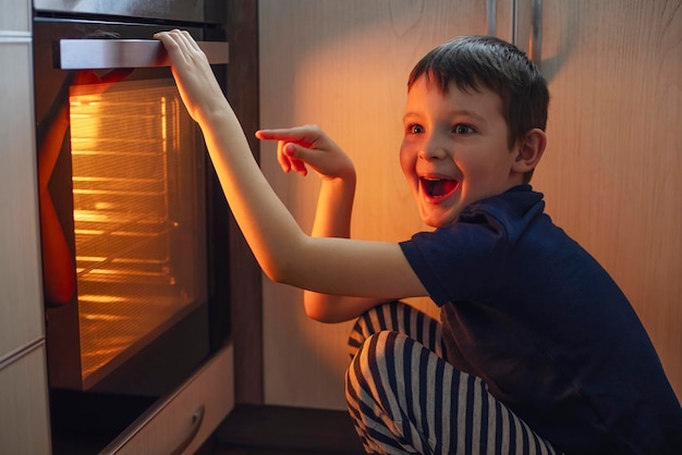 A child is sitting near the oven in the kitchen and waiting