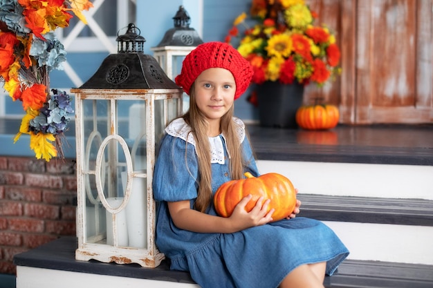 Child is sitting next to pumpkins near door of house. Autumn home decor