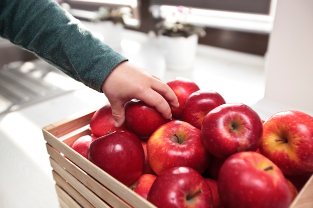 The child is taking the juicy red apple from the basket