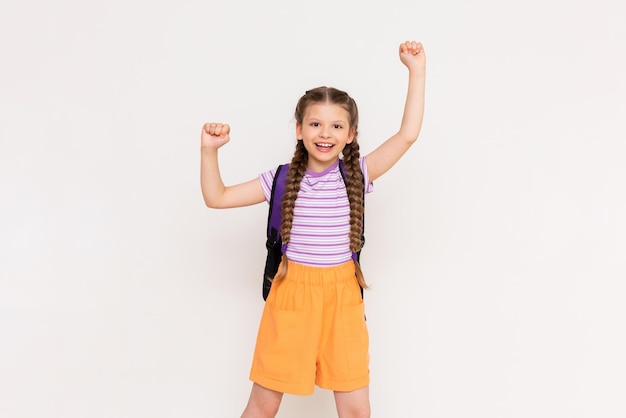 The child is very happy about the summer educational courses for children A beautiful little girl holds up her fists and smiles broadly on a white isolated background