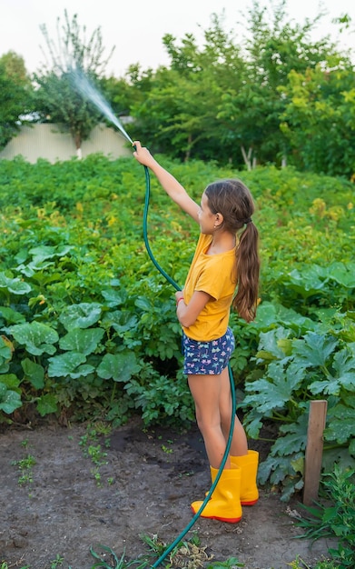 The child is watering the garden with a hose Selective focus