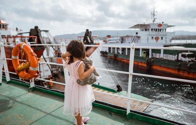 Photo a child joyfully watching boats from a ferry with a beautiful scenic ocean view