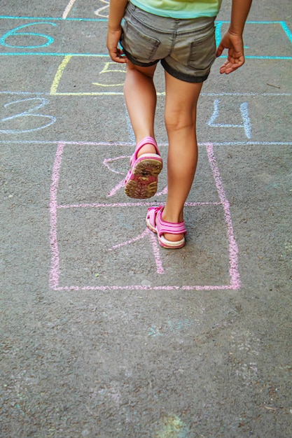 Child jumping classics on the pavement. Selective focus.