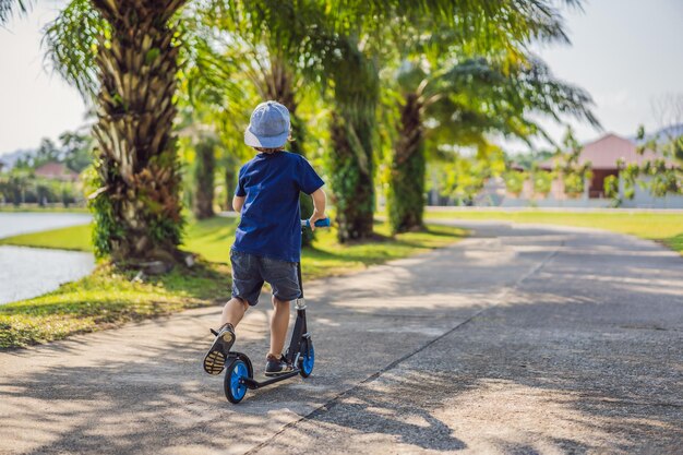 Child on kick scooter in park Kids learn to skate roller board Little boy skating on sunny summer day Outdoor activity for children on safe residential street Active sport for preschool kid