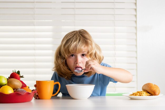 Child in the kitchen at the table eating vegetable and fruits during the dinner lunch hunger appetit