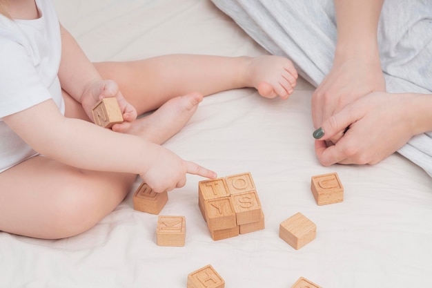 The child laid out the word toys made of wooden cubes closeup A small child learns the English alphabet learns to read Early child development educational games