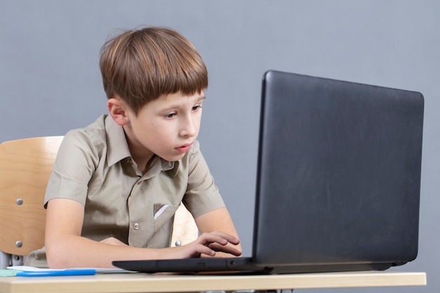 The child at the laptop The boy looks at the monitor screen