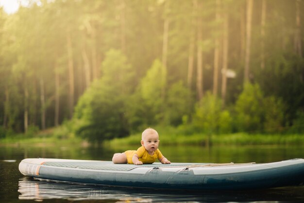 The child lies floating on the water on a large sup board Water sports