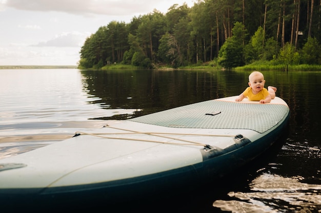 The child lies floating on the water on a large sup board Water sports