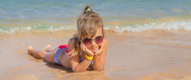 Child lies in the sand on the beach. 