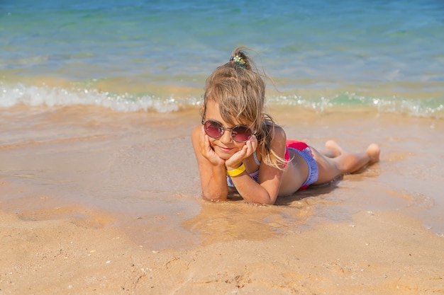 Child lies in the sand on the beach