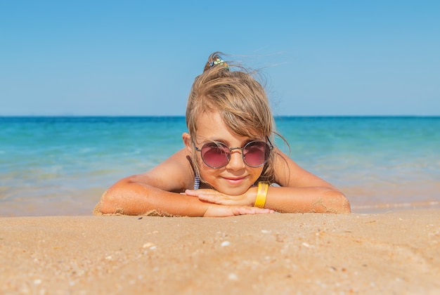 Child lies in the sand on the beach