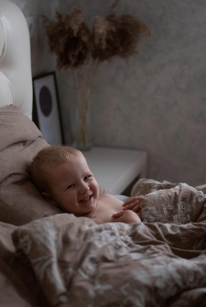 the child lies and smiles. lucky boy. the child is in bed. morning.