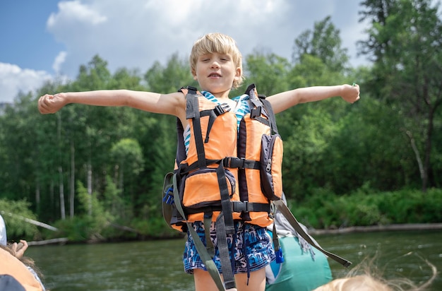 Child in life jacket is rafting with his family along a mountain river Summer family adventures Rafting on a mountain river on a raft