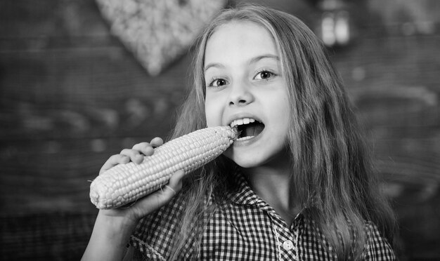 Child little girl enjoy farm life Organic gardening Grow your own organic food Kid farmer with harvest wooden background Harvest festival concept Girl kid at farm market with organic vegetables