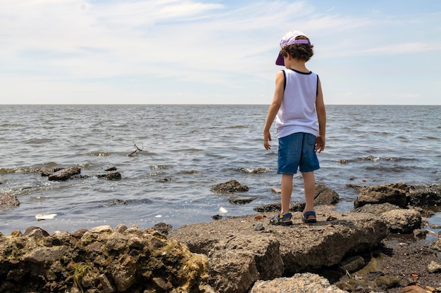 Child looking at polluted river from the shore environmental concept