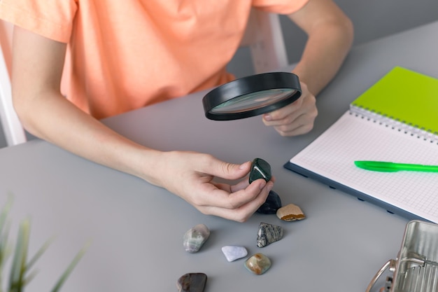 Child looks at his collection of semiprecious stones with magnifying glass Education concept