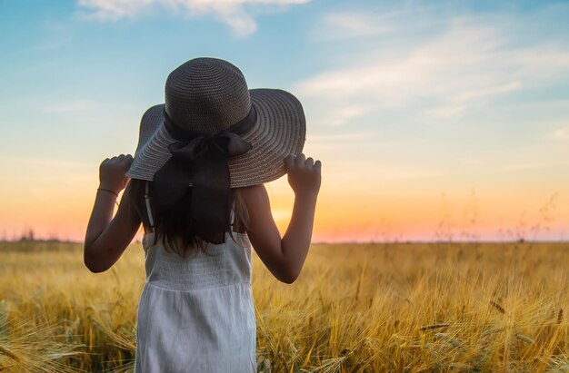 A child looks at the sunset in a wheat field. Selective focus.