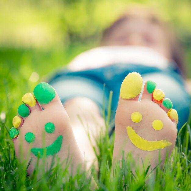 Child lying on green grass. Kid having fun outdoors in spring park