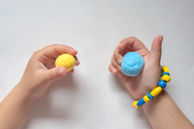 A child make the flag of Ukraine dough Child with plasticine in the colors of the flag of Ukraine in hands Children's creativity DIY holiday handicraft and craft tools Pray for Ukraine