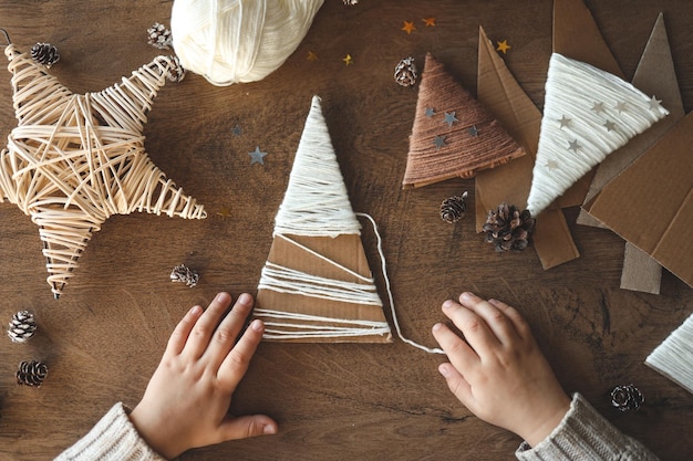 Photo child makes christmas decoration from yarn