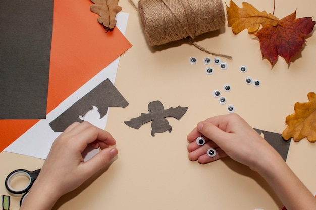 A child makes a Halloween craft in the form of a bat with eyes