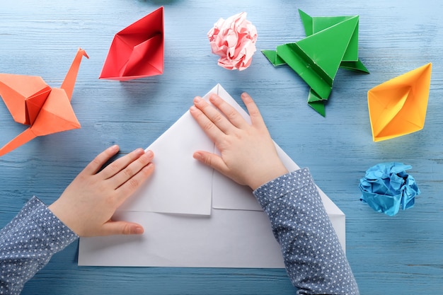 Photo child makes origami on a blue table