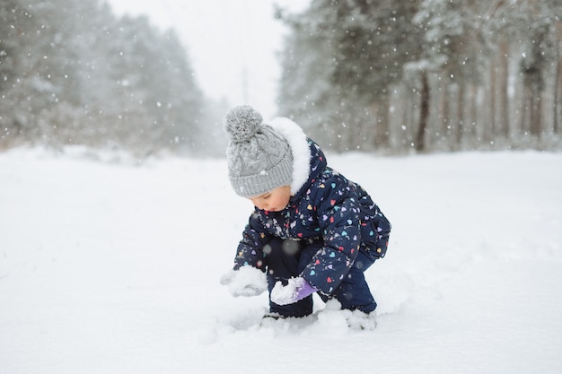 Child outdoors playing in snow. Snowy winter weather.