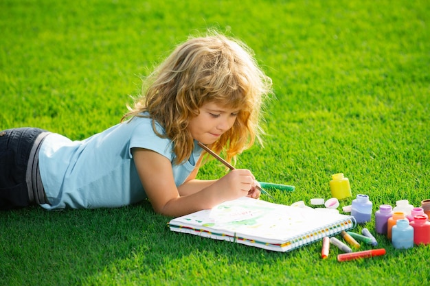 Child painting drawing art portrait of smiling happy kid enjoying art and craft drawing in backyard