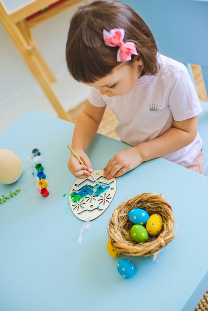 Child paints eggs on wooden workpiece eggs