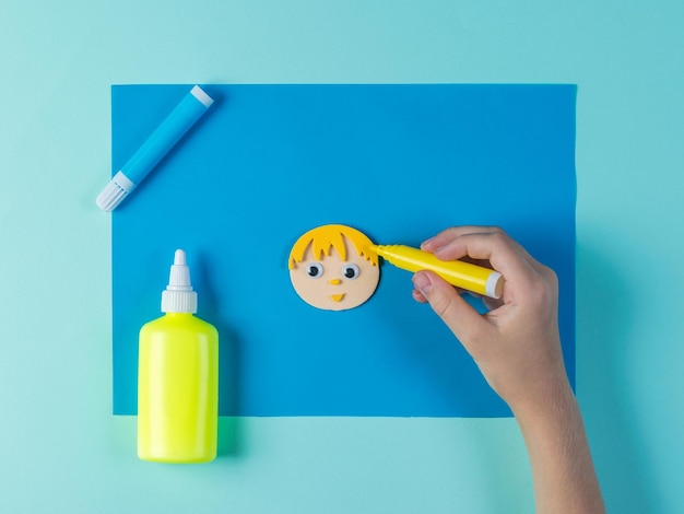 The child paints the hair on paper applications in the shape of a man