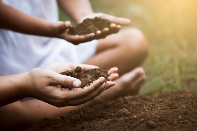 Child and parent holding soil and preparing soil for plant the tree together