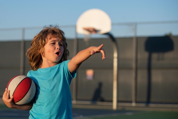 Child playing basketball. Healthy children lifestyle. Kids little boy playing basketball. Child pointing showing gesture.