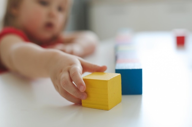 child playing and building with colorful wooden toy bricks on white wooden table Early learning