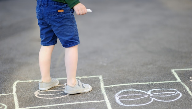 Child playing hopscotch game on playground outdoors on a sunny day