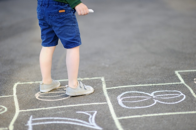 Child playing hopscotch game on playground outdoors on a sunny day