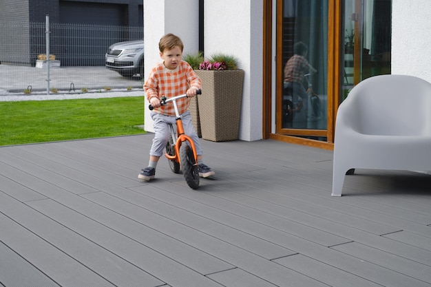 Child playing racing on bike in the home yard outdoors