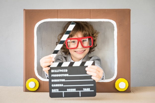 Child playing with cardboard box TV. Kid having fun at home. Communication concept