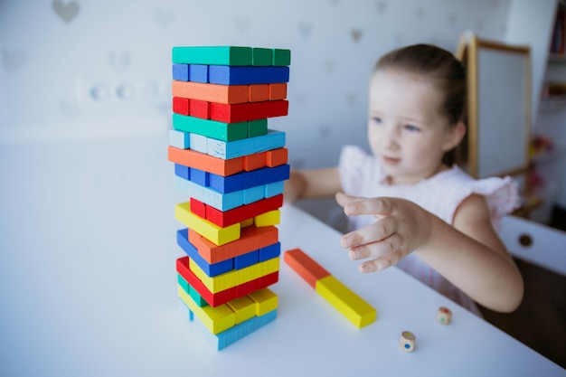 Child playing with colorful wooden bricks on the white table background