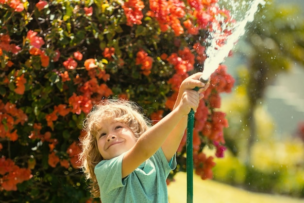 Child playing with garden hose in backyard funny excited kid having fun with spray of water on yard