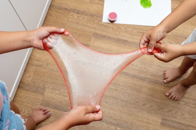 Child playing with red color slime, gunge, gel in hands