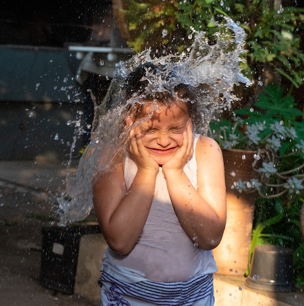 Child playing in the yard with water in the Brazilian summer