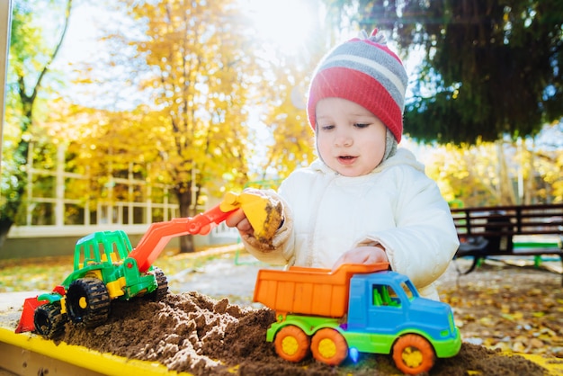 The child plays cars on the playground