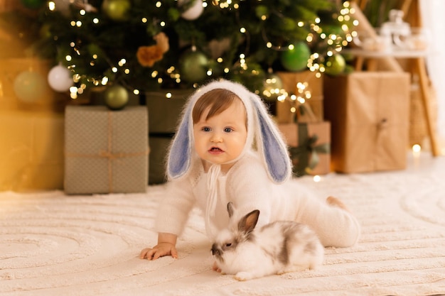 the child plays with a bunny on the background of the Christmas tree